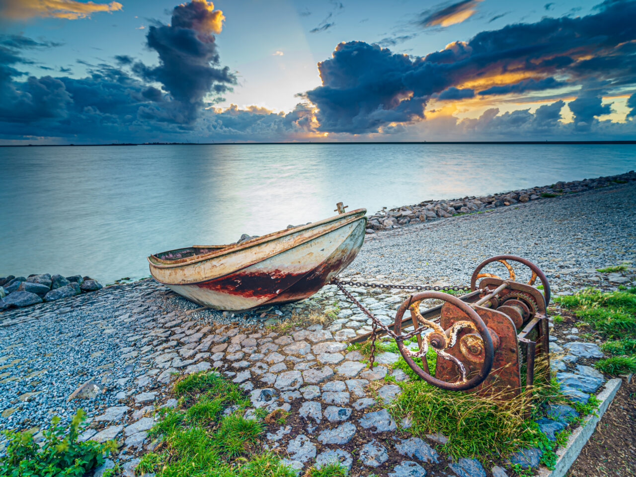 An old rusty fishing boat on the slope along the shore of the lake